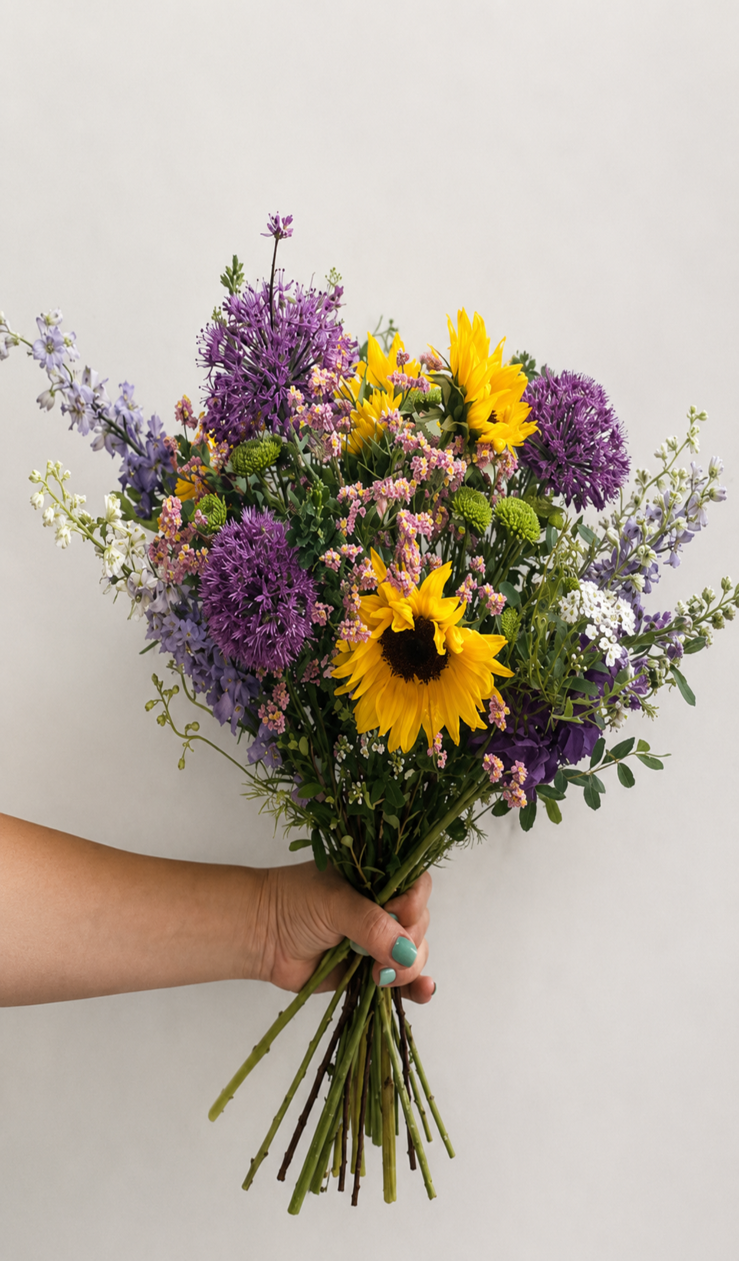 Bouquet of flowers held by a person against a plain background